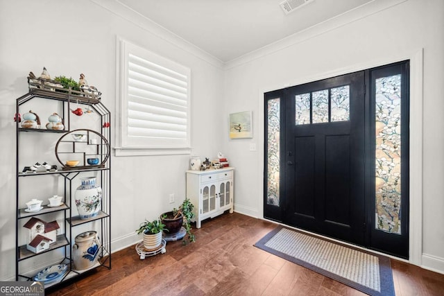 entrance foyer with baseboards, wood finished floors, visible vents, and ornamental molding