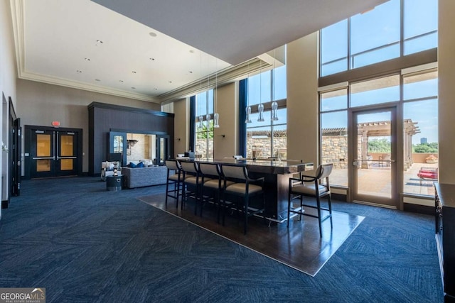 dining space with a high ceiling, carpet floors, and ornamental molding