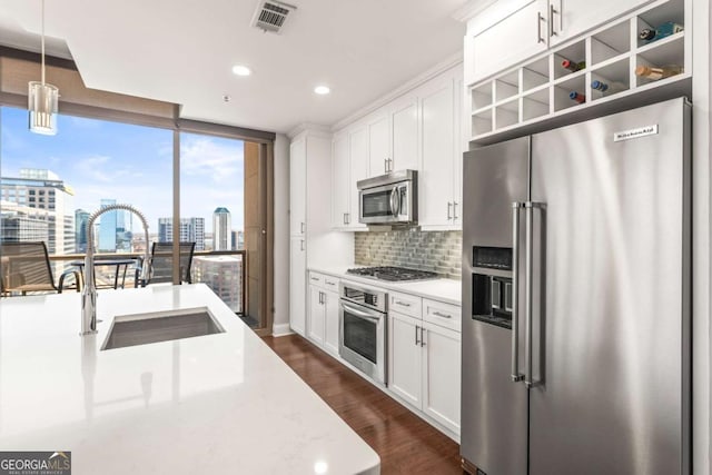 kitchen with visible vents, backsplash, dark wood finished floors, appliances with stainless steel finishes, and a sink