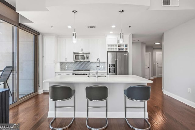 kitchen featuring a center island with sink, visible vents, a sink, light countertops, and appliances with stainless steel finishes