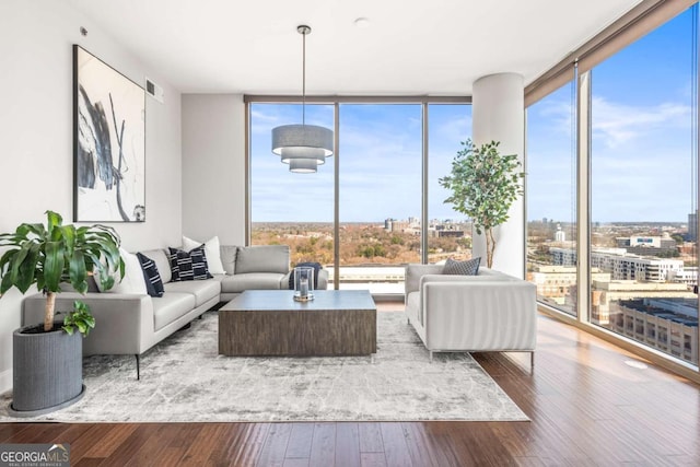 living room featuring a wall of windows, visible vents, and hardwood / wood-style floors