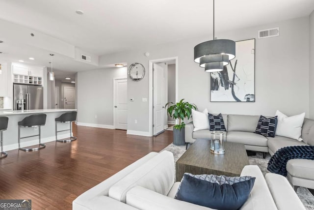 living room with dark wood-type flooring, baseboards, and visible vents