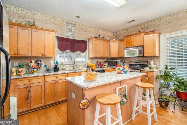 11 Tallulah Ct, Jonesboro, GA 30236 - kitchen with stainless steel appliances, wallpapered walls, plenty of natural light, a kitchen island, and light wood finished floors