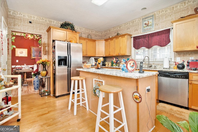 11 Tallulah Ct, Jonesboro, GA 30236 - kitchen featuring stainless steel appliances, wallpapered walls, a center island, light wood-style floors, and a kitchen bar