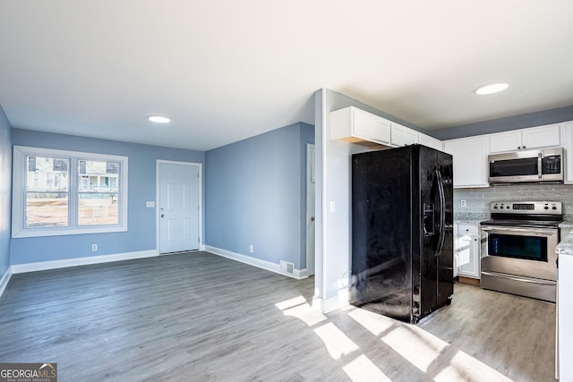 kitchen with baseboards, stainless steel appliances, white cabinetry, light wood-type flooring, and backsplash