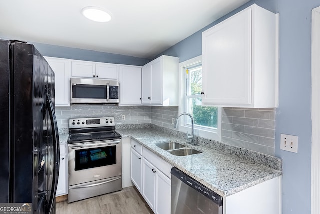 kitchen with a sink, appliances with stainless steel finishes, white cabinets, and light wood finished floors