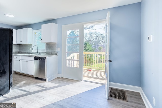 doorway to outside featuring light wood finished floors, visible vents, baseboards, and a sink