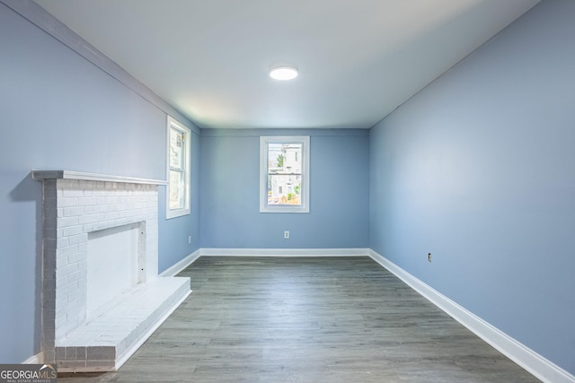 unfurnished living room with a fireplace, baseboards, and wood finished floors