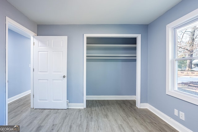 unfurnished bedroom with wood finished floors, baseboards, and a closet