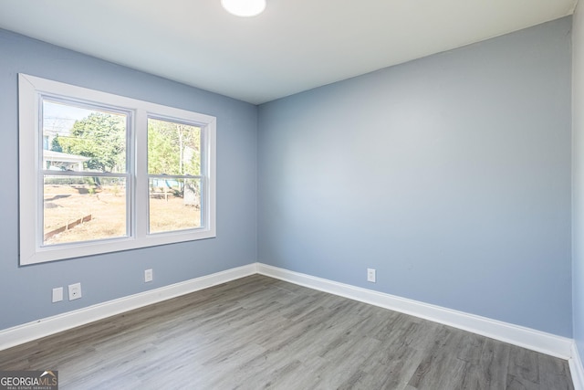 spare room featuring baseboards and wood finished floors