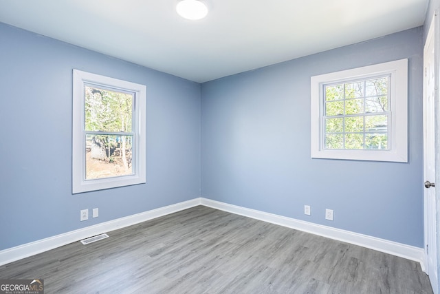 empty room with visible vents, baseboards, and wood finished floors