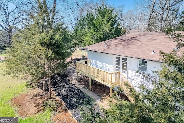 rear view of house with a wooden deck and roof with shingles