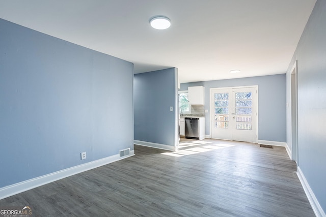 unfurnished living room featuring visible vents, french doors, baseboards, and wood finished floors