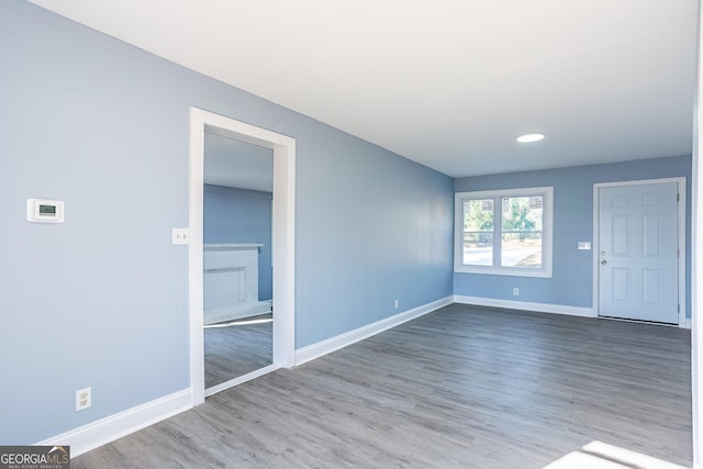 unfurnished room with a fireplace, baseboards, and wood finished floors