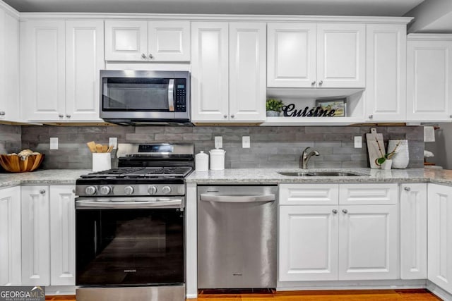 kitchen featuring white cabinets, open shelves, stainless steel appliances, and a sink