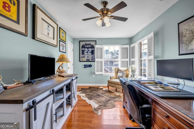 home office featuring baseboards, light wood-type flooring, and a ceiling fan