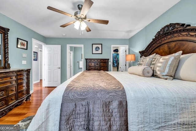 bedroom featuring a ceiling fan, wood finished floors, a closet, baseboards, and a spacious closet