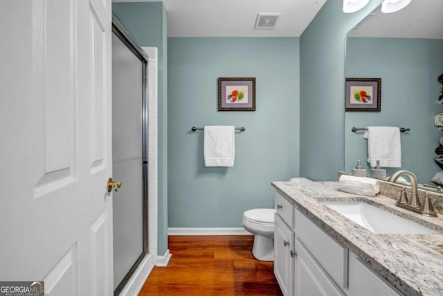 bathroom featuring a shower with shower door, visible vents, wood finished floors, baseboards, and vanity