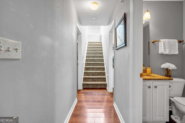 corridor featuring stairs, wood finished floors, and baseboards