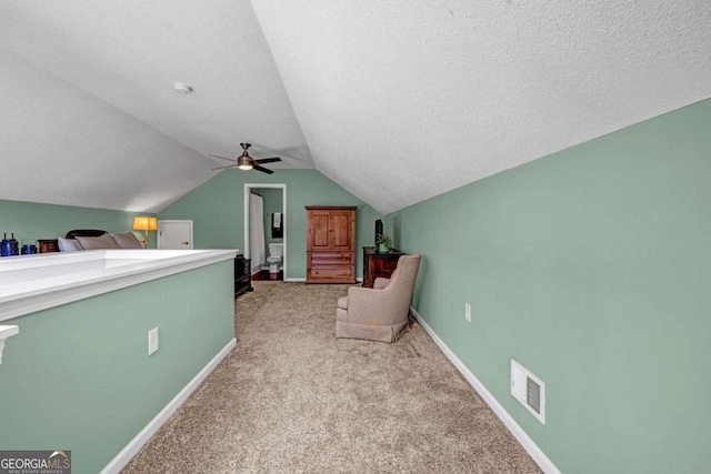 sitting room with baseboards, visible vents, lofted ceiling, a textured ceiling, and light colored carpet