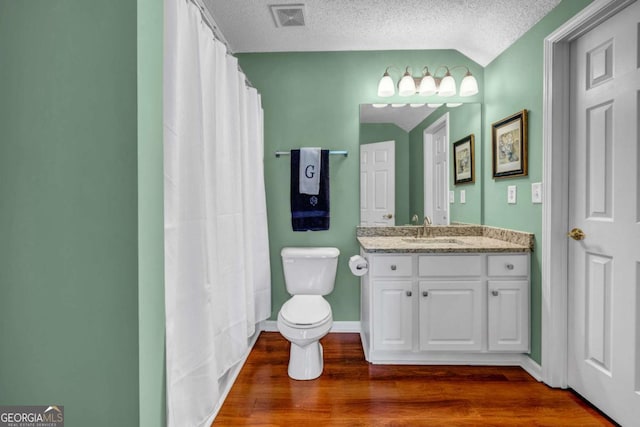 full bathroom featuring vanity, wood finished floors, visible vents, lofted ceiling, and a textured ceiling