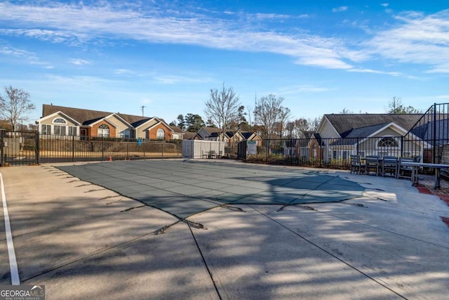 pool with a patio area, a residential view, and fence