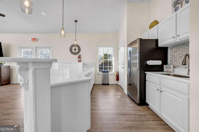 kitchen featuring decorative backsplash, light wood-type flooring, white cabinetry, and a sink