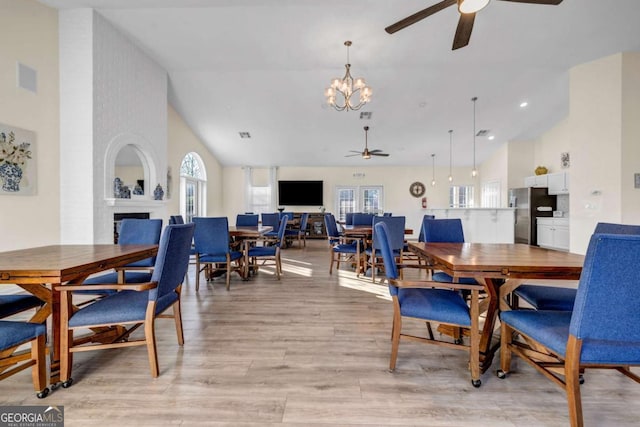 dining area with visible vents, a brick fireplace, light wood-style flooring, high vaulted ceiling, and a ceiling fan