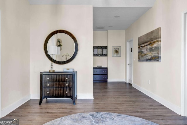 hallway with visible vents, baseboards, and wood finished floors