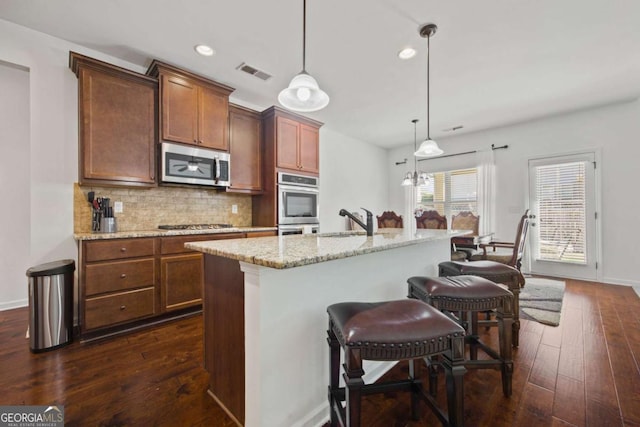 kitchen featuring visible vents, dark wood-type flooring, decorative backsplash, stainless steel appliances, and a sink