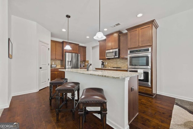 kitchen featuring visible vents, a kitchen breakfast bar, dark wood-style floors, stainless steel appliances, and a sink