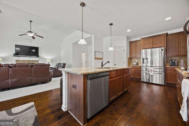 kitchen featuring dark wood-style floors, a sink, stainless steel appliances, open floor plan, and tasteful backsplash