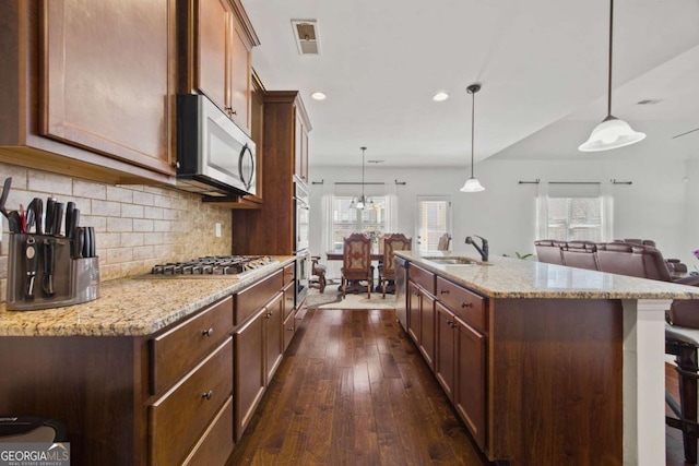 kitchen with backsplash, dark wood-type flooring, open floor plan, stainless steel appliances, and a sink