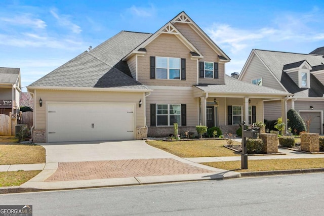 craftsman-style home featuring decorative driveway, brick siding, an attached garage, and roof with shingles