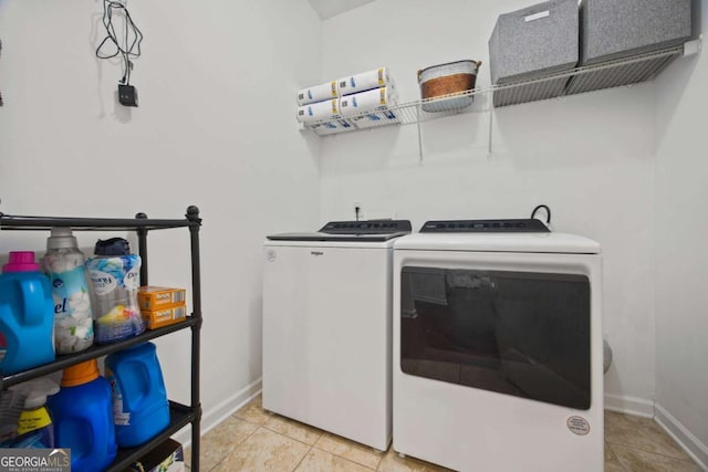 clothes washing area with laundry area, light tile patterned floors, washing machine and dryer, and baseboards