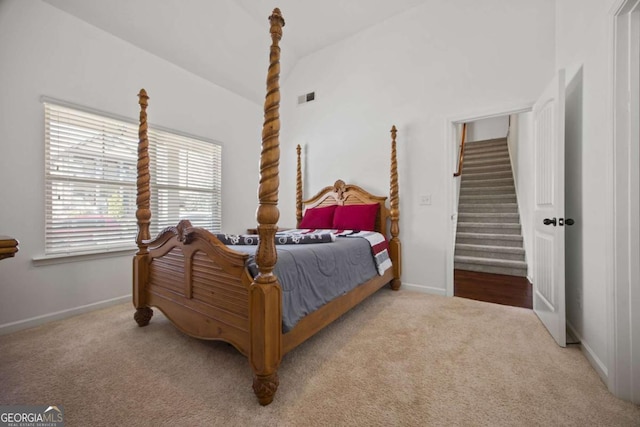 carpeted bedroom with lofted ceiling, baseboards, and visible vents