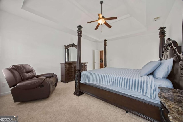 bedroom featuring a ceiling fan, a tray ceiling, and light colored carpet