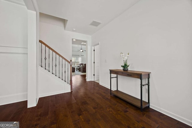 corridor featuring stairway, visible vents, baseboards, and hardwood / wood-style flooring