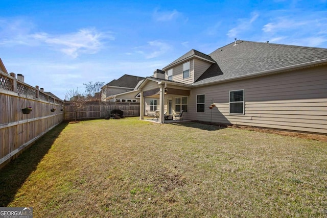 rear view of house with a patio area, a lawn, a fenced backyard, and roof with shingles