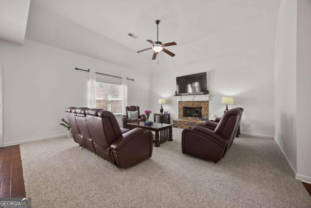 living area with visible vents, baseboards, a fireplace with raised hearth, and a ceiling fan