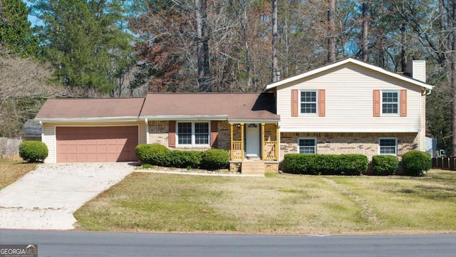 split level home with driveway, an attached garage, a front yard, brick siding, and a chimney