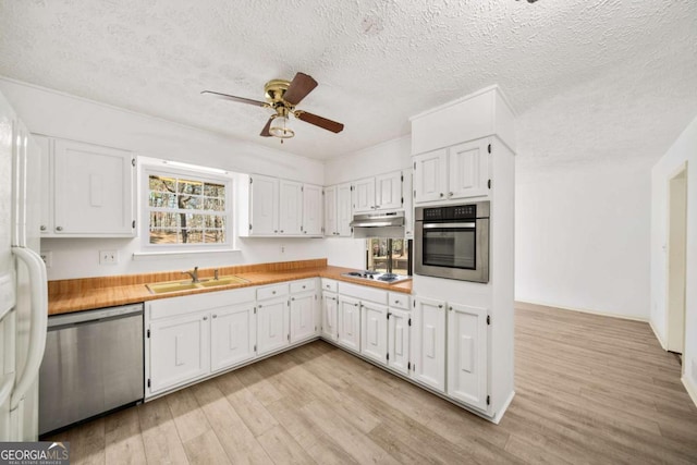 kitchen with a sink, stainless steel appliances, light wood-style floors, white cabinets, and light countertops