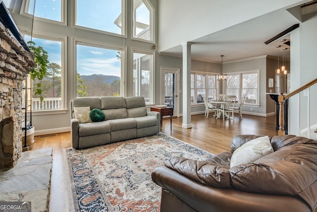 living room featuring crown molding, stairs, a fireplace, wood finished floors, and a notable chandelier