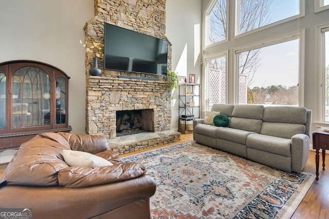 living room featuring a fireplace, a towering ceiling, and wood finished floors