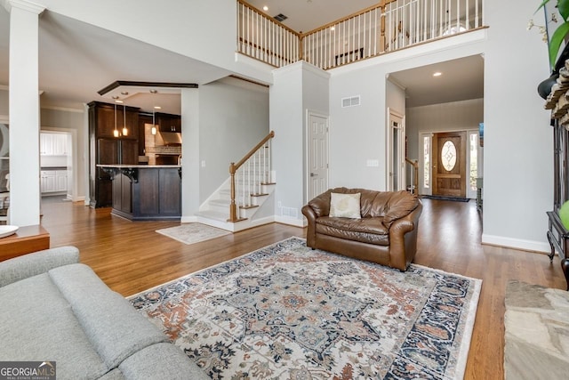 living room featuring visible vents, baseboards, wood finished floors, and stairs