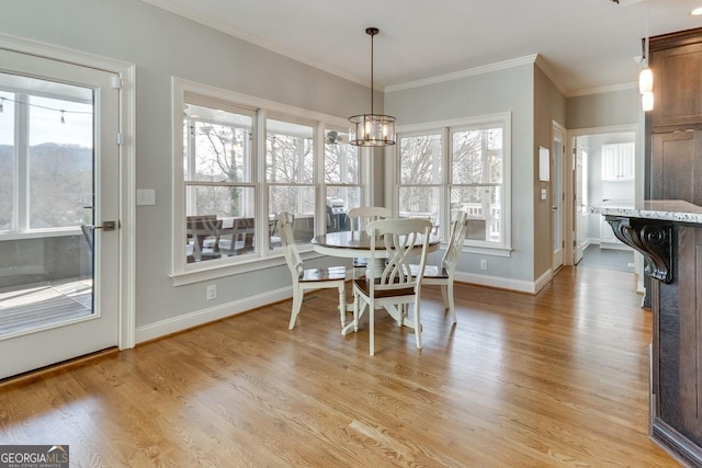 dining area featuring a chandelier, baseboards, light wood-style floors, and ornamental molding