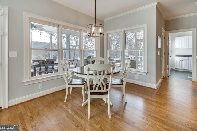 dining space featuring baseboards, light wood-style floors, an inviting chandelier, and ornamental molding