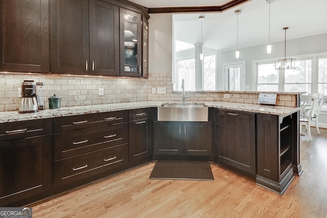 kitchen featuring plenty of natural light, a peninsula, light wood-style floors, and a sink