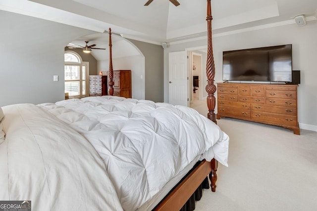 bedroom with a ceiling fan, arched walkways, a raised ceiling, light colored carpet, and vaulted ceiling