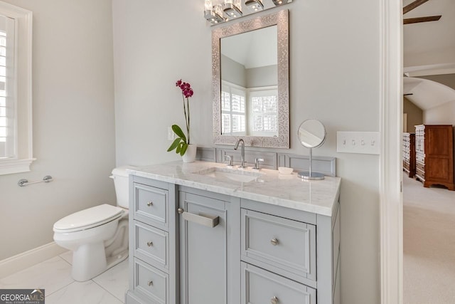 bathroom with vanity, baseboards, lofted ceiling, toilet, and marble finish floor